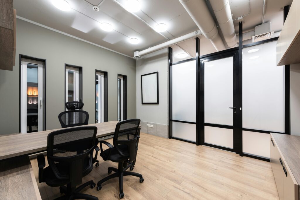 Wooden table and black office chairs placed in spacious room in new contemporary workplace