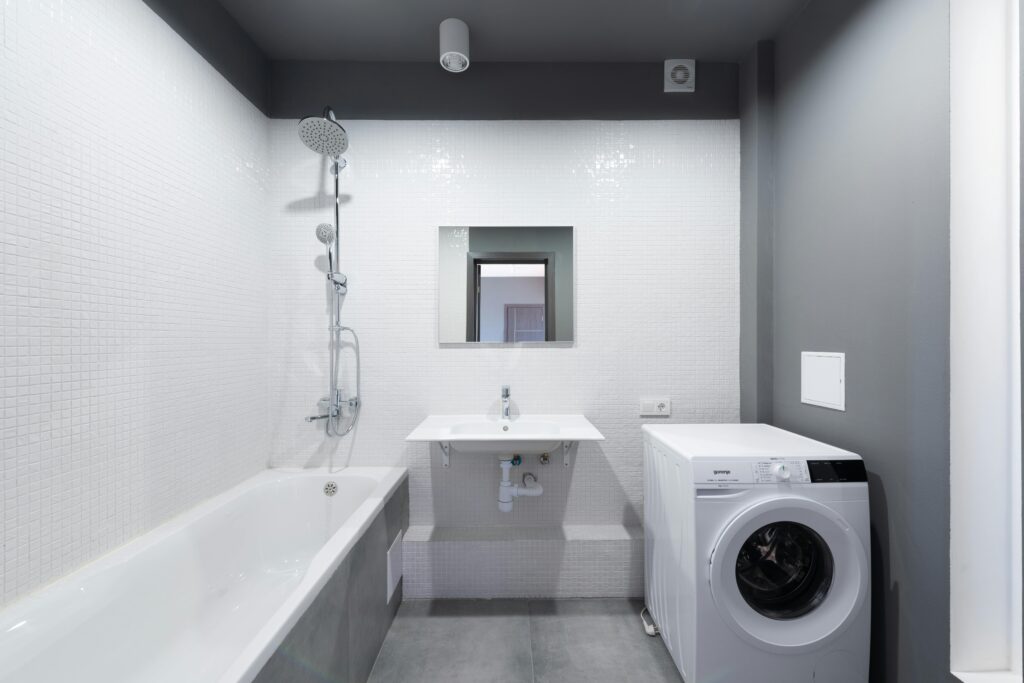 Modern bathroom design featuring bathtub, sink, and washing machine.