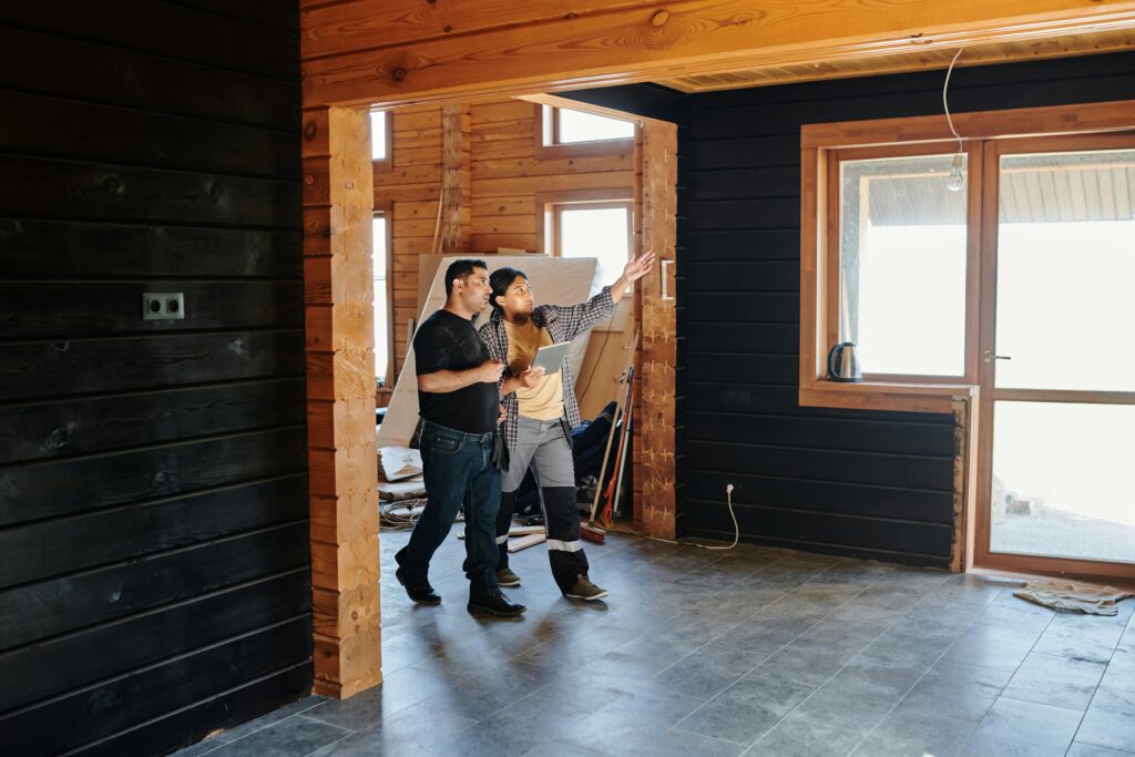 Two adults discussing home renovation in a partially constructed modern wooden interior.